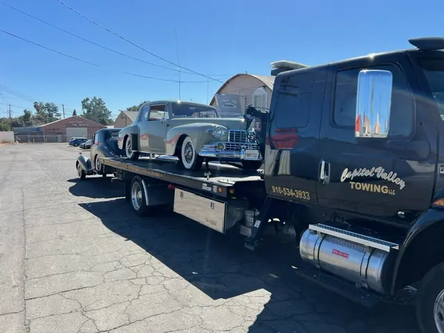 Black Capitol Valley tow truck with a classic car