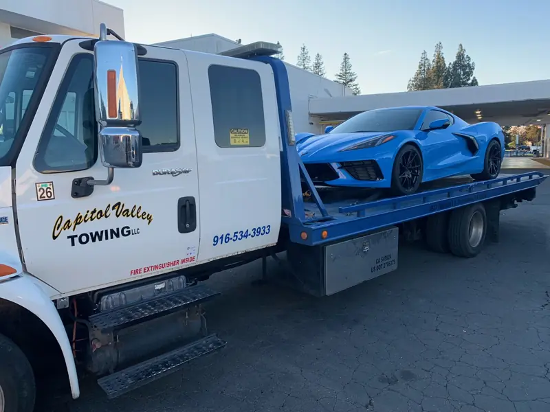 Blue Corvette secured on a flatbed tow truck