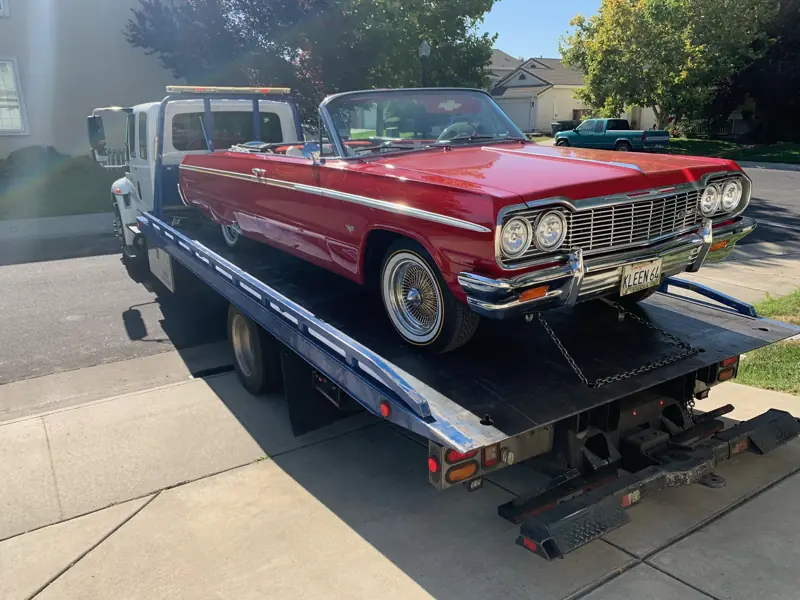 Red classic Impala being loaded onto a flatbed