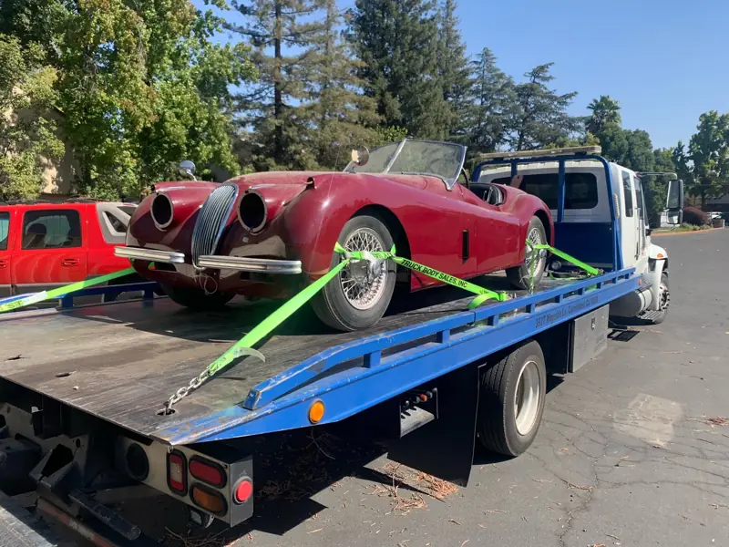 Vintage red roadster strapped down on a flatbed